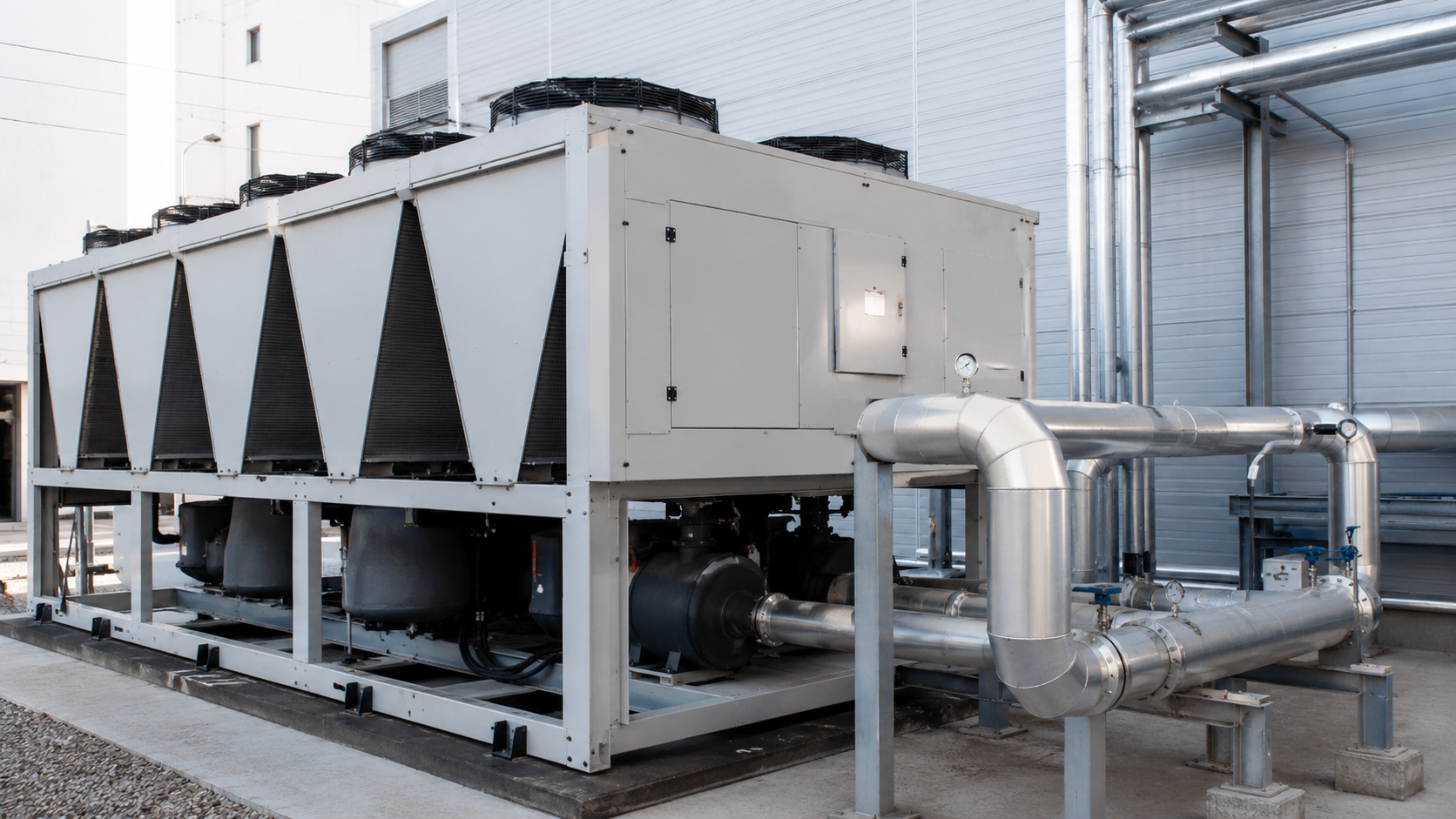 Hệ thống chiller giải nhiệt gió đặt ngoài trời với dàn giải nhiệt, quạt, đường ống và khu vực kỹ thuật nhà xưởng.